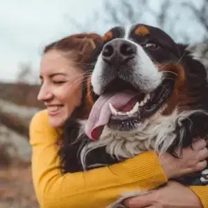 woman giving brown and black dog a hug
